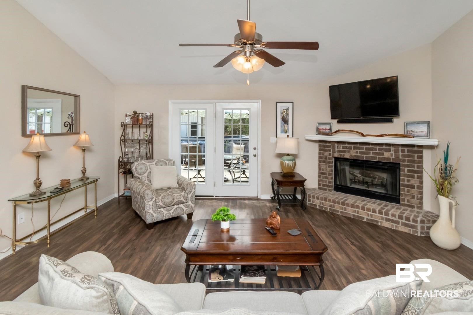 11528 Mocking Bird Lane Fairhope, AL 36532 - Photo 2 of 45 Living room with vaulted ceiling, dark wood-style floors, a brick fireplace, and ceiling fan