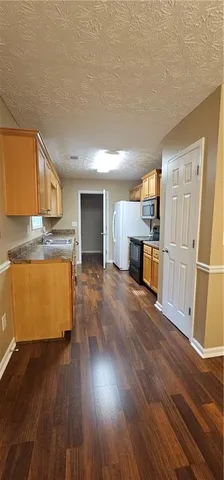 a room with wooden floors and kitchen view