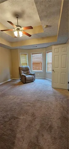 an empty room with chandelier fan and windows