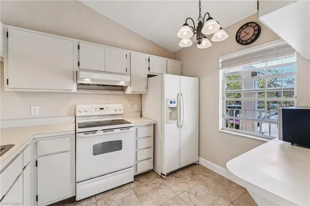 a kitchen with stainless steel appliances granite countertop a white refrigerator a stove a dining table and chairs with wooden floor