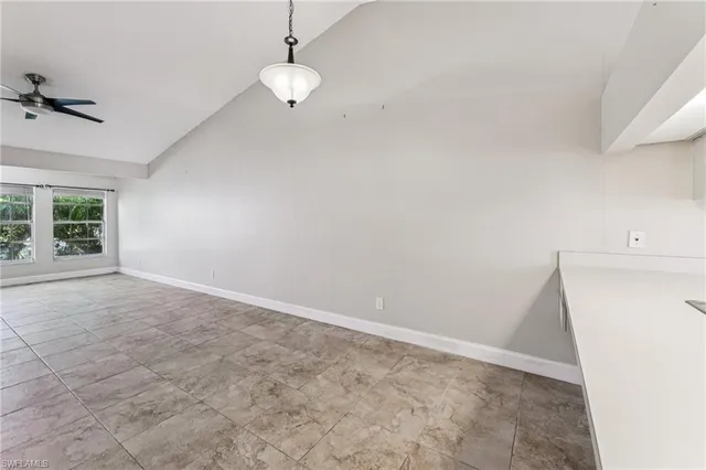 an empty room with windows and ceiling fan