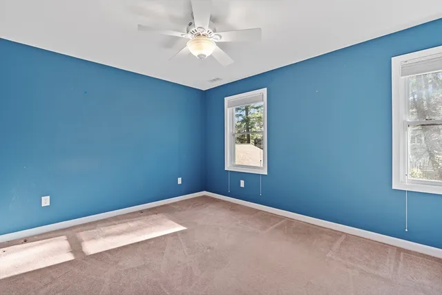 an empty room with windows and fan