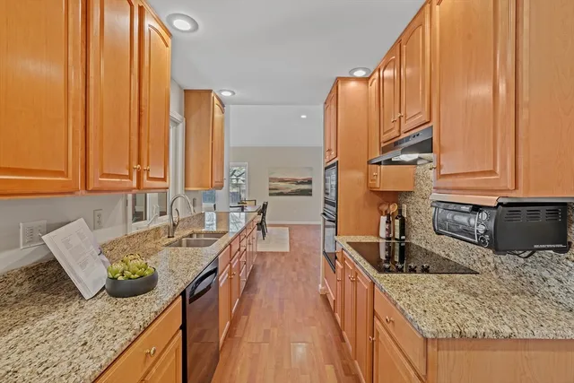 a kitchen with stainless steel appliances granite countertop a sink a stove and a wooden cabinets