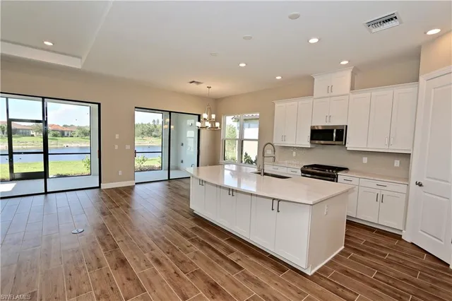 a large kitchen with stainless steel appliances granite countertop a large stove a sink dishwasher and a microwave with wooden floor