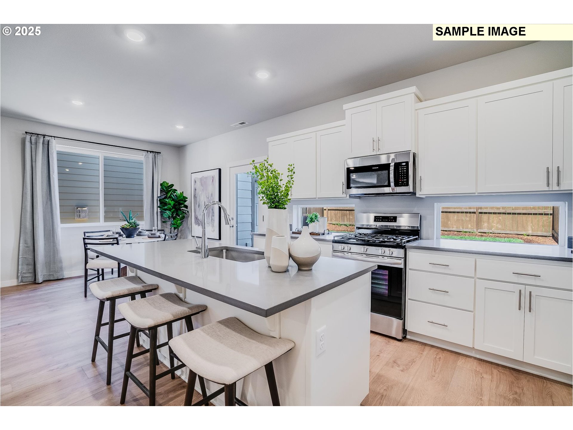 23809 Southwest Black Tortoise Terrace Tualatin, OR 97062 - Photo 10 of 26 a kitchen with stainless steel appliances kitchen island granite countertop a stove a sink a microwave a dining table and chairs