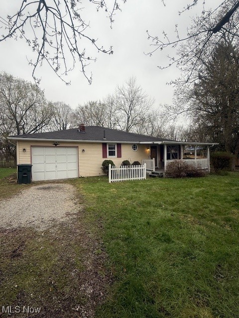 Single story home with covered porch, a garage, a chimney, dirt driveway, and a front lawn