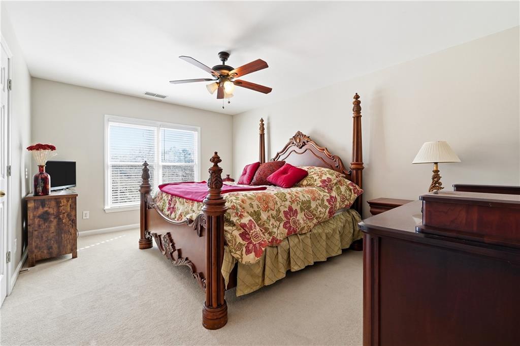 585 Tilbury Drive Suwanee, GA 30024 - Photo 24 of 46 a bedroom with a bed and a chandelier