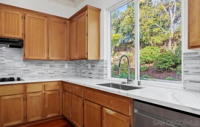a kitchen with stainless steel appliances wooden cabinets a sink and a window