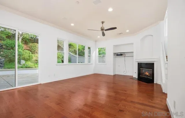 a view of an empty room with a window and kitchen view