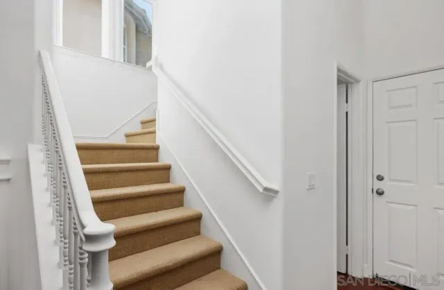 a view of staircase with white walls and white door