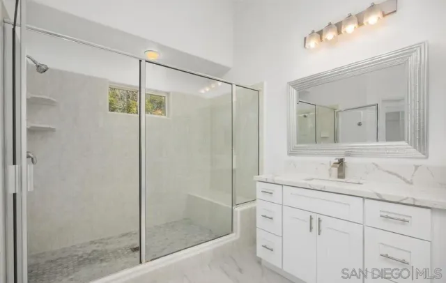 a bathroom with a shower sink vanity and mirror