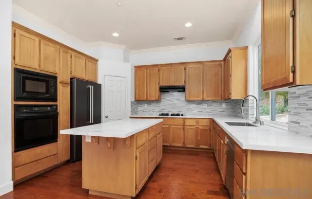 a kitchen with stainless steel appliances a sink a stove a refrigerator a sink a oven with wooden floor and cabinets