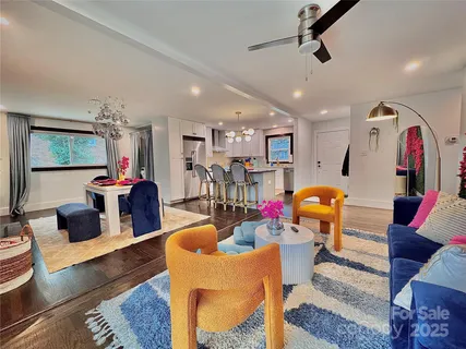 a living room with furniture kitchen view and a chandelier