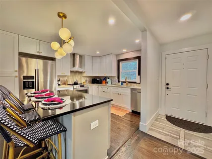 a kitchen view with stainless steel appliances granite countertop a stove refrigerator and cabinets