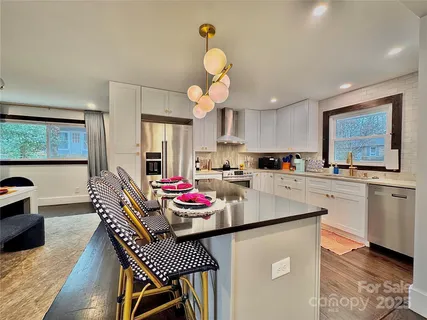 a kitchen with stainless steel appliances granite countertop a sink dishwasher a stove a dining table and chairs with wooden floor