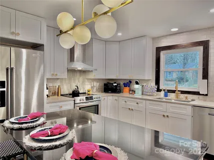 a kitchen with stainless steel appliances kitchen island granite countertop a sink a stove and a wooden floors