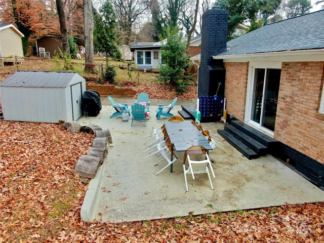 a view of a patio with table and chairs near a barbeque