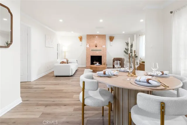 a living room with furniture a fireplace and a dining table with wooden floor