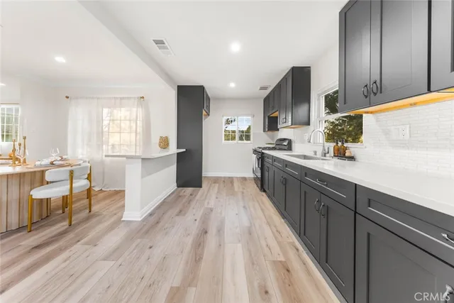 a large kitchen with stainless steel appliances wooden floors and large window