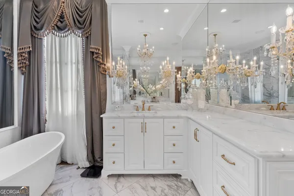 a spacious bedroom with a bed a chandelier and dresser