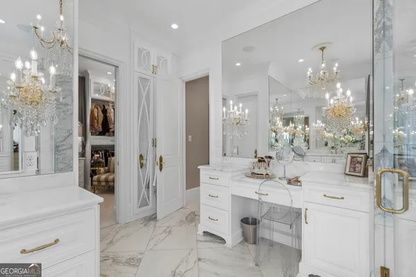 a spacious bedroom with a bed a chandelier and a mirror on the dresser