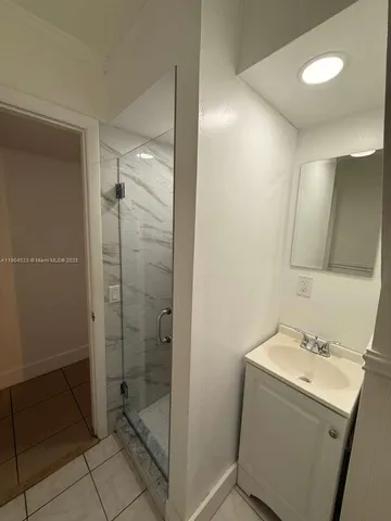 a bathroom with a shower sink and mirror