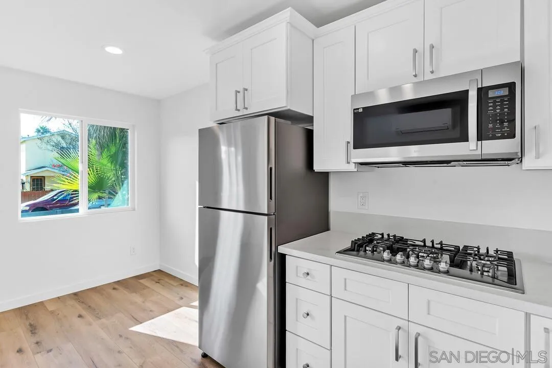 4922 Muir Avenue San Diego, CA 92107 - Photo 25 of 69 a kitchen with stainless steel appliances a refrigerator a stove a microwave cabinets and wooden floor