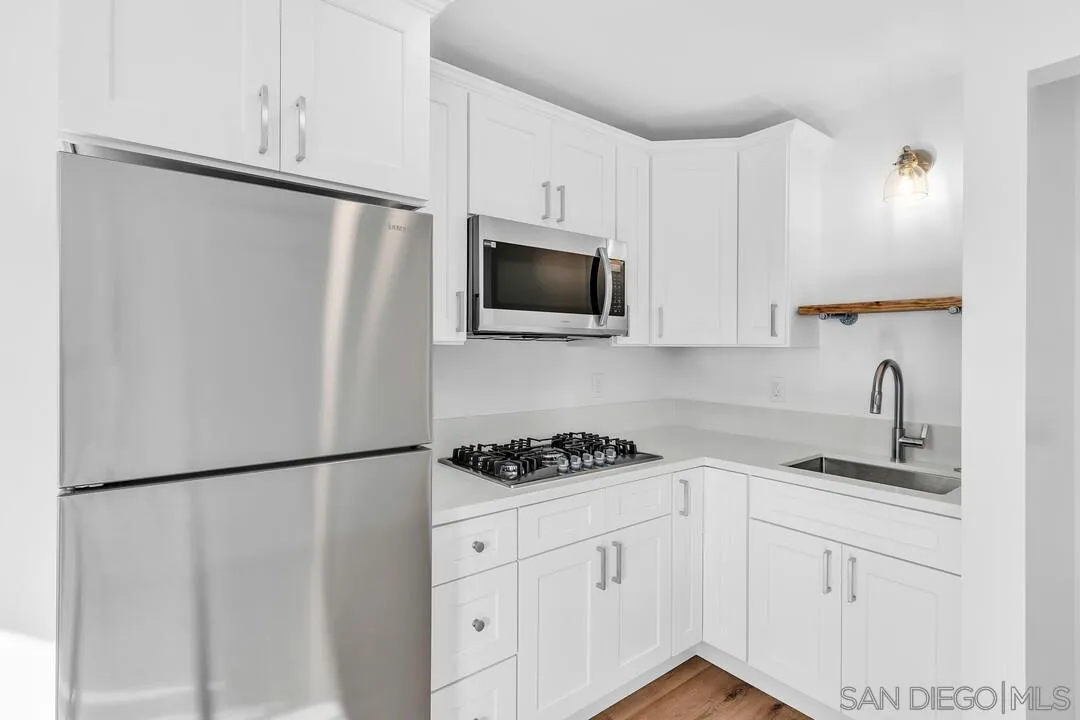 4922 Muir Avenue San Diego, CA 92107 - Photo 34 of 69 a kitchen with white cabinets and stainless steel appliances