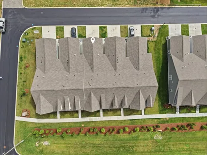 an aerial view of a residential houses with outdoor space and a lake view