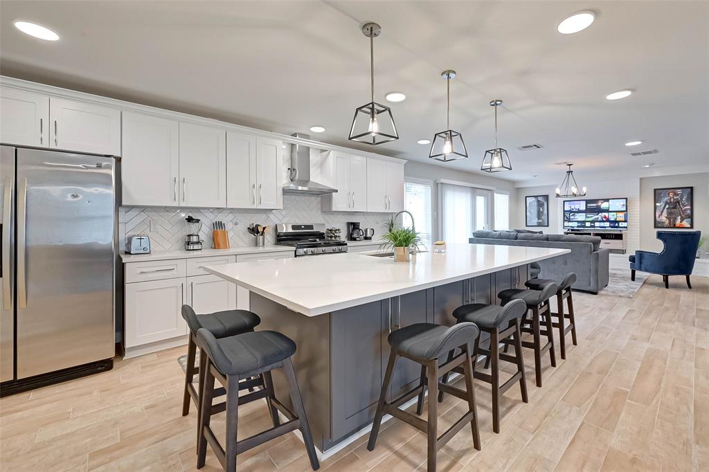 a kitchen with stainless steel appliances a table chairs refrigerator and cabinets