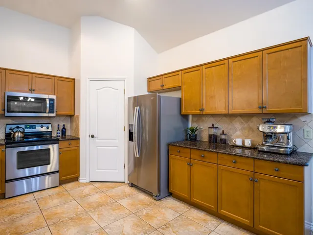 a kitchen with stainless steel appliances granite countertop a refrigerator and a stove top oven