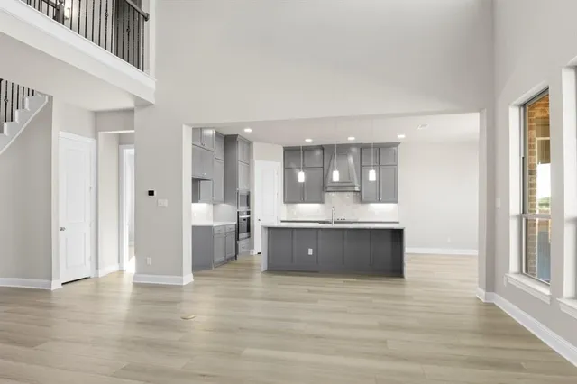 a large kitchen with stainless steel appliances kitchen island granite countertop a refrigerator a sink dishwasher a stove and white countertops with wooden floor