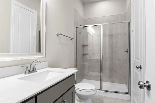 a bathroom with a shower sink vanity mirror and toilet