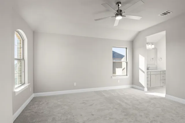 an empty room with windows and ceiling fan
