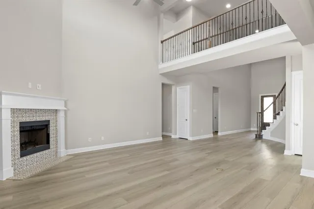 a view of an empty room with wooden floor and a fireplace