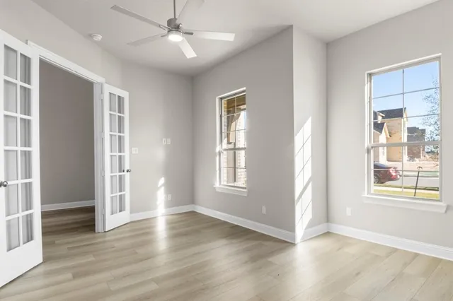 an empty room with wooden floor cabinet and windows