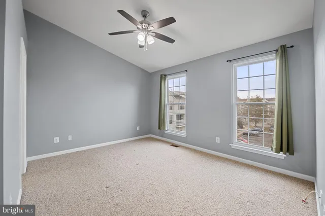 an empty room with windows and ceiling fan