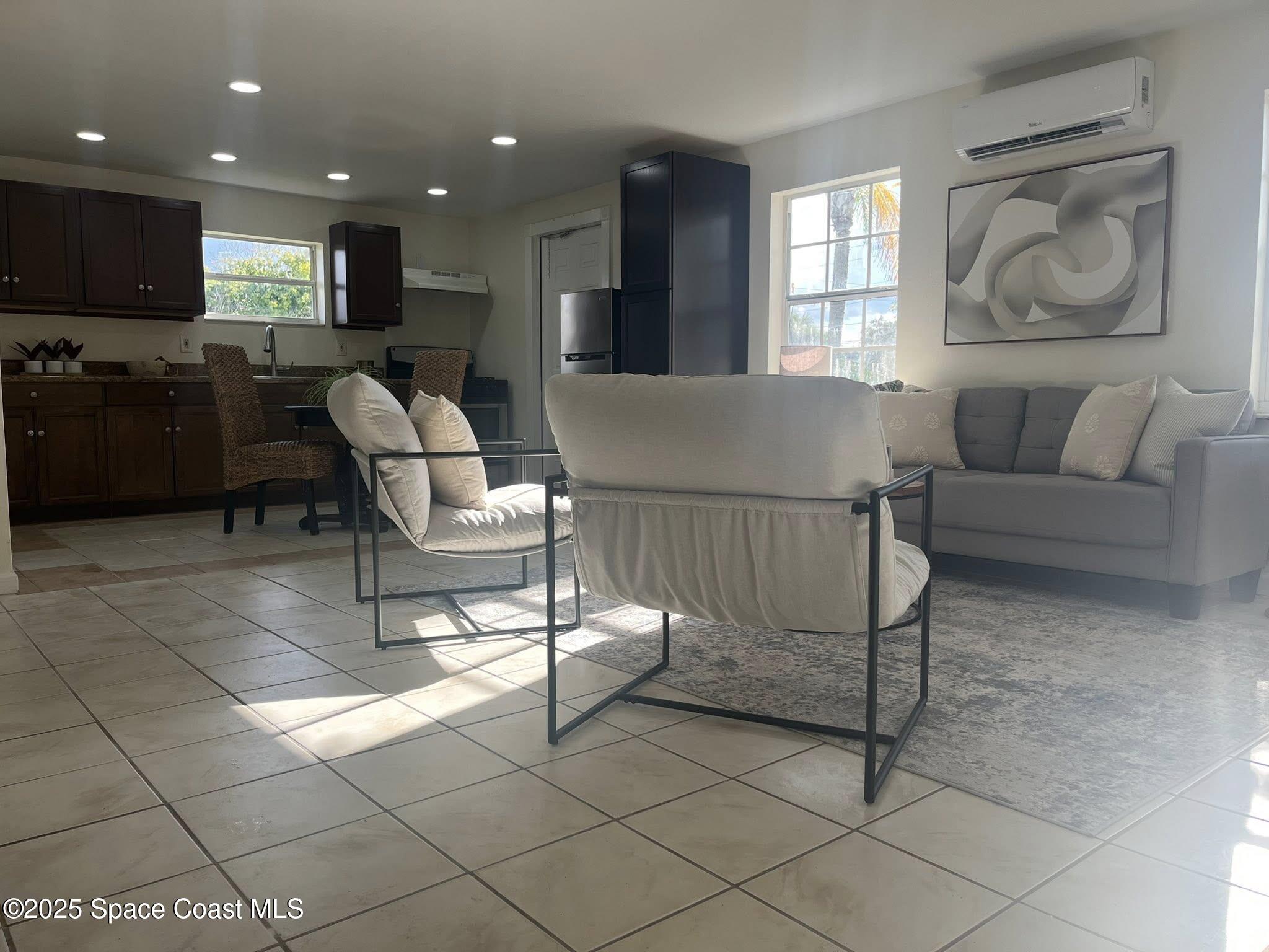 2027 Wallace Avenue, Unit IN Melbourne, FL 32935 - Photo 2 of 5 a living room with couches a flat screen tv and kitchen view