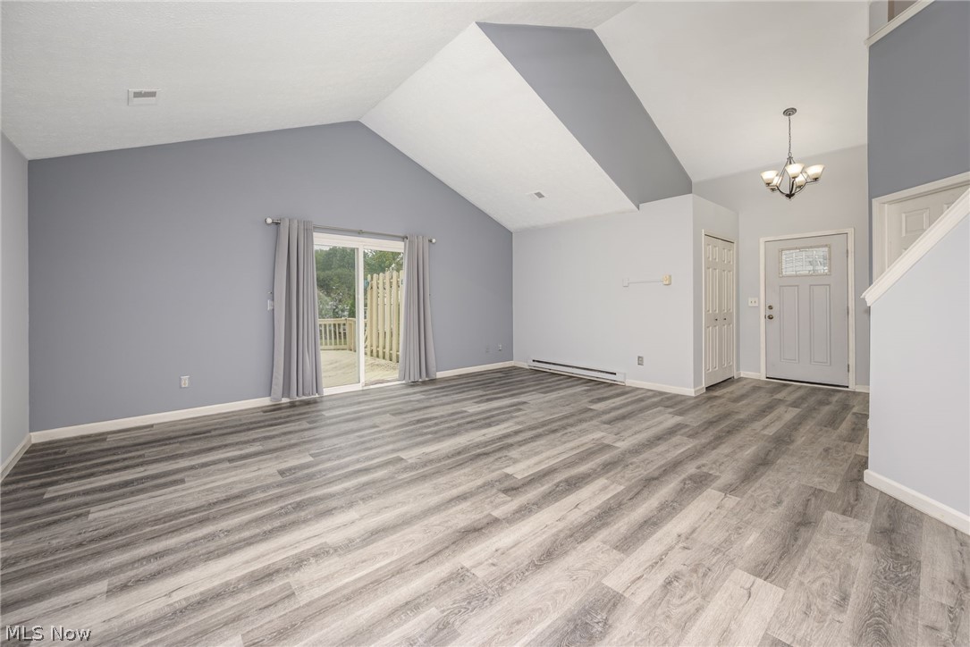 5203 Cline Road Kent, OH 44240 - Photo 22 of 35 Vaulted ceiling with accent paint, wood-finish flooring, sliding glass door, front door with decorative glass insert, and a five-light chandelier