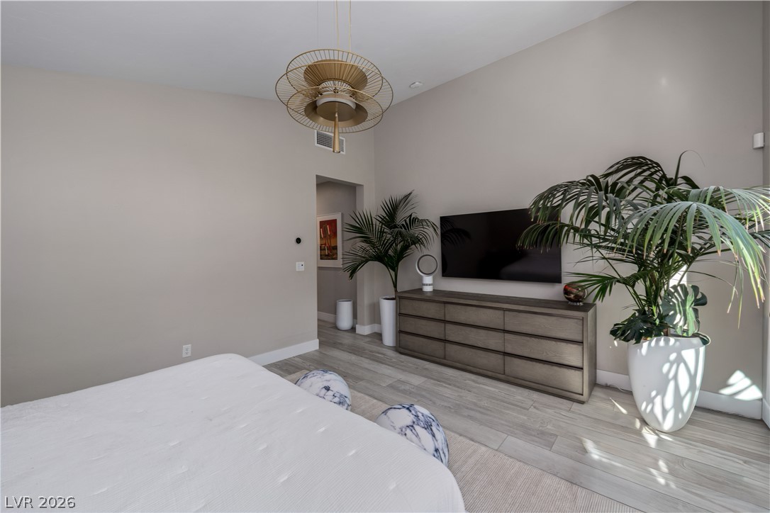 9719 Starlight Ridge Avenue Las Vegas, NV 89148 - Photo 11 of 25 A striking modern chandelier illuminates this spacious bedroom, featuring durable wood-look tile flooring.