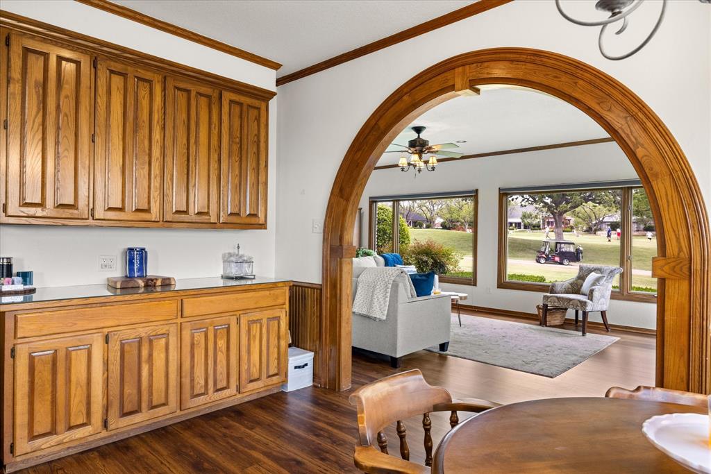 8911 Bontura Road Granbury, TX 76049 - Photo 13 of 39 Dining area featuring crown molding, arched walkways, dark wood-style floors, and a ceiling fan