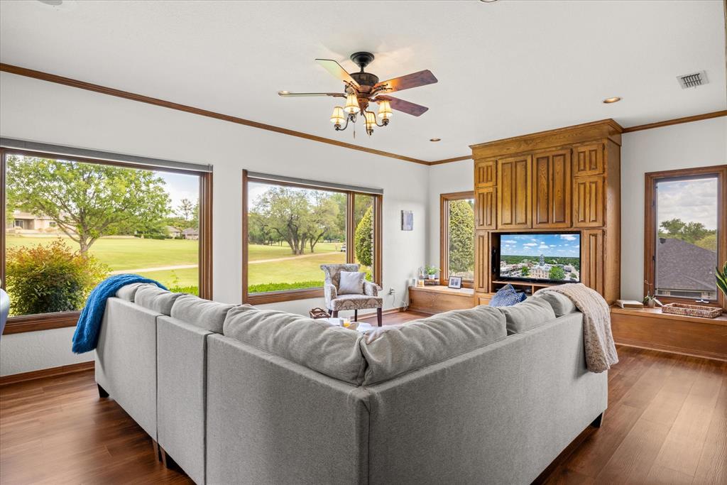 8911 Bontura Road Granbury, TX 76049 - Photo 20 of 39 Living room with ceiling fan, dark wood-type flooring, ornamental molding, view of golf course, and recessed lighting