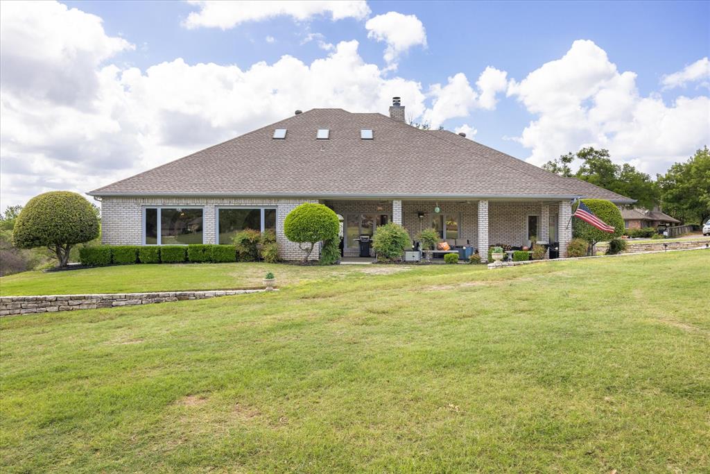 8911 Bontura Road Granbury, TX 76049 - Photo 33 of 39 View of front facade featuring a front yard, brick siding, a chimney, and a patio