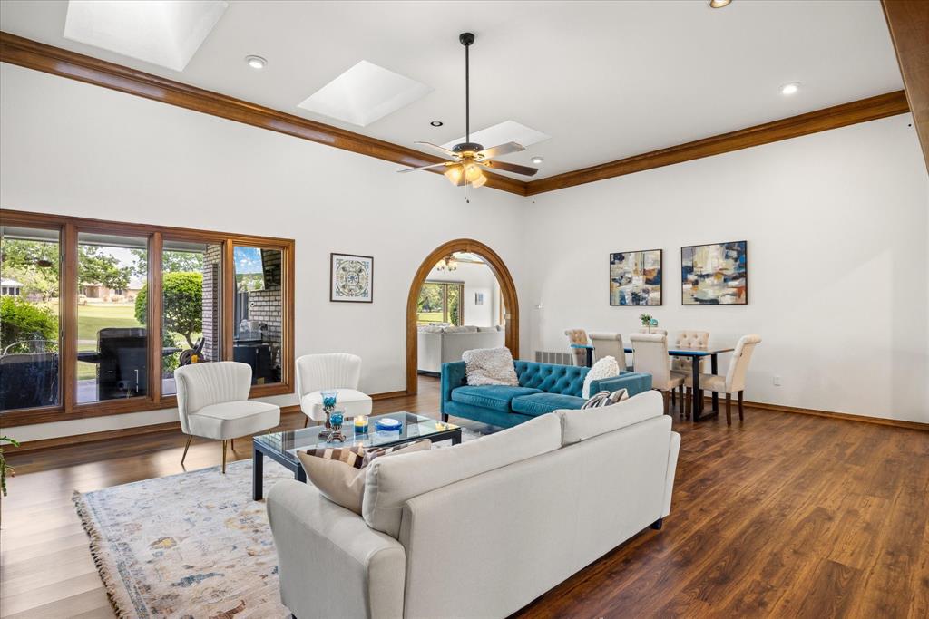 8911 Bontura Road Granbury, TX 76049 - Photo 4 of 39 Living room featuring crown molding, wood finished floors, a ceiling fan, arched walkways, and a skylight