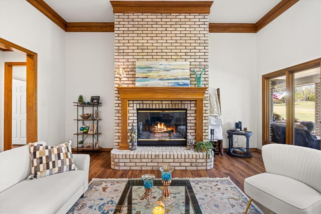 8911 Bontura Road Granbury, TX 76049 - Photo 5 of 39 Living room with crown molding, wood finished floors, and a brick fireplace
