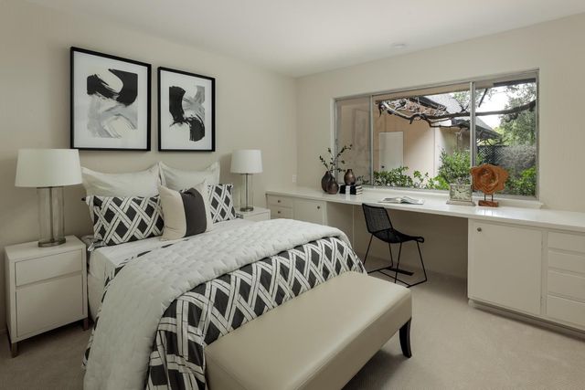 a bedroom with a bed a table and painting on the wall