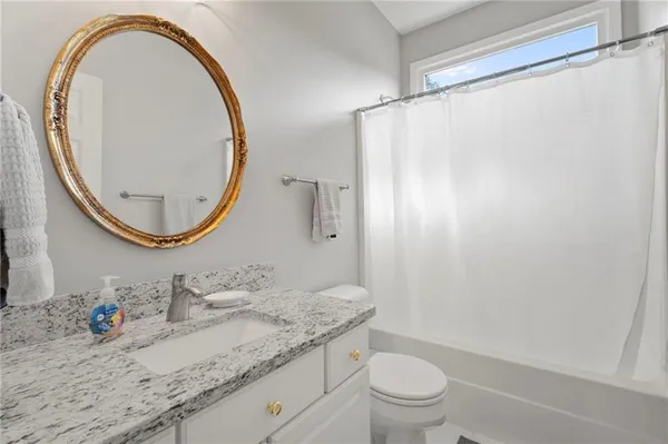 a bathroom with a granite countertop sink mirror vanity and a toilet