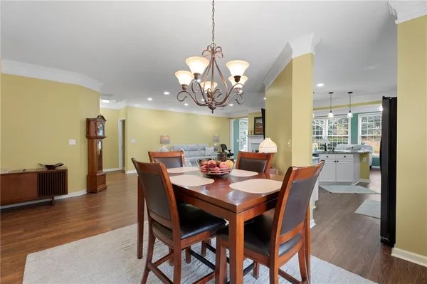 a dining room with wooden floor a chandelier a wooden table and chairs