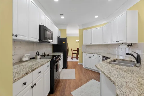 a kitchen with granite countertop a sink a stove and cabinets