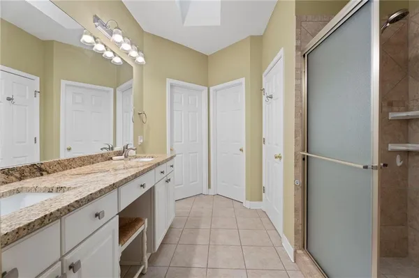 a spacious bathroom with a granite countertop sink a mirror and a shower